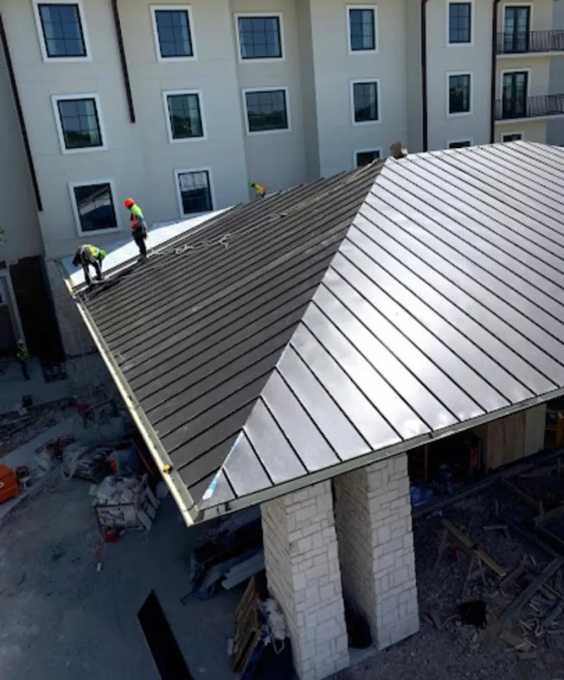 Crew installing standing seam metal roof panels on a commercial project in Rockingham